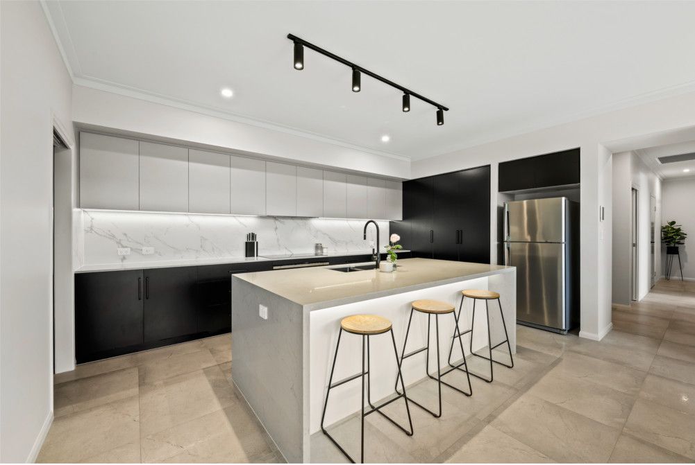 A Kitchen with A Large Island and Stools — Peter Betros Homes in Highfields, QLD