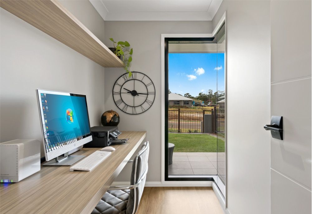 A home office with a computer and a clock on the wall. — Peter Betros Homes in Highfields, QLD