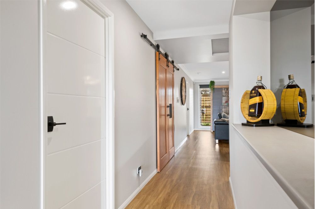 A hallway with a sliding barn door leading to a living room. — Peter Betros Homes in Highfields, QLD