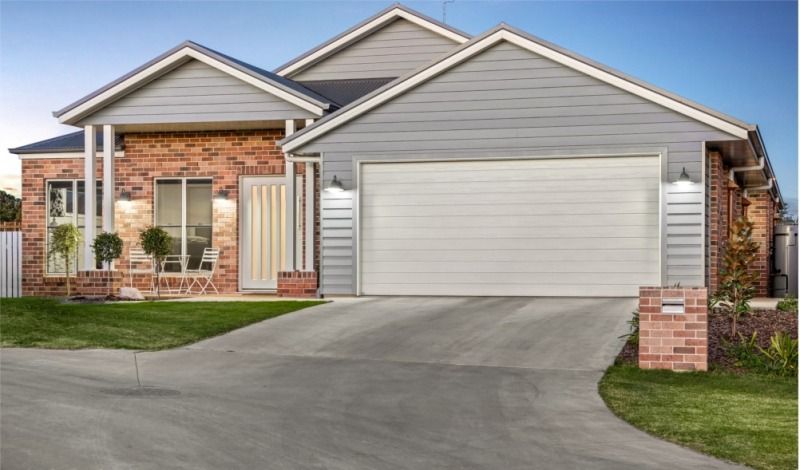 A Large Brick House With a White Garage Door — Peter Betros Homes in Highfields, QLD
