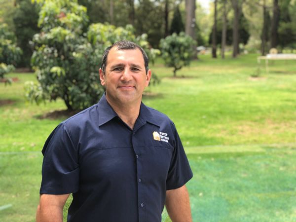 A Man in a Blue Shirt is Standing in a Park — Peter Betros Homes in Highfields, QLD
