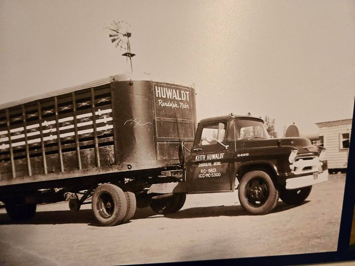 A red semi truck is pulling a white trailer in a field.