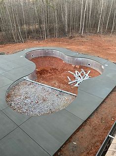 A swimming pool is being built in the middle of a dirt field.