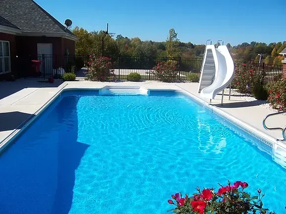 A large swimming pool with a slide in the backyard