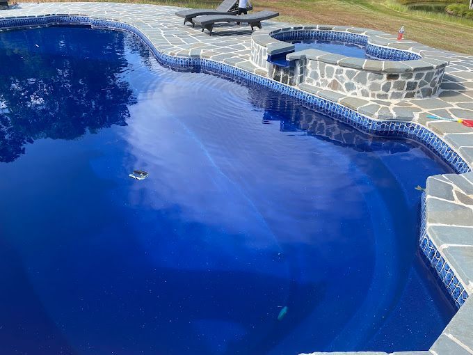 A large blue swimming pool with a hot tub in the background.