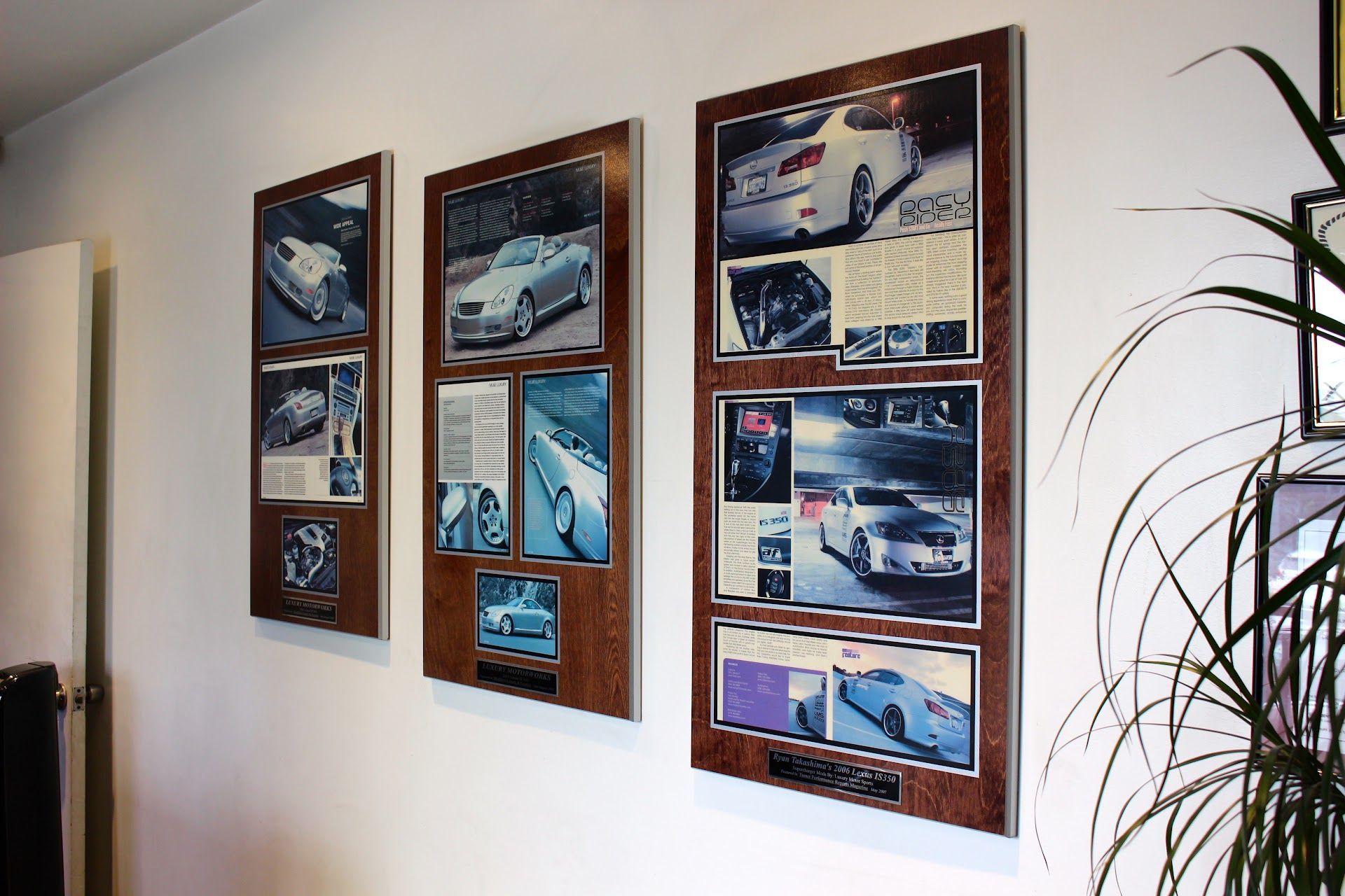Three framed collages of vehicle photos hanging on a light wall near a plant | Luxury Motorworks