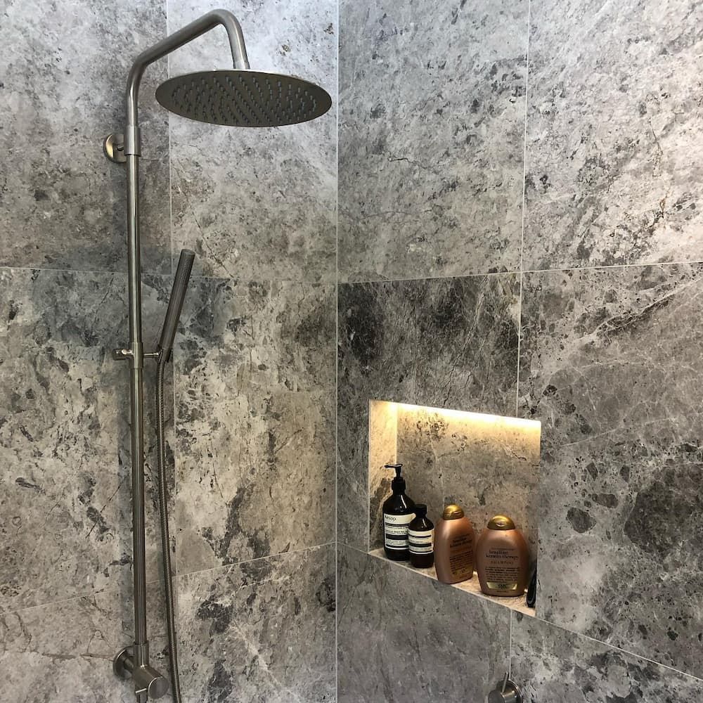 A Bathroom With a Shower Head and a Shelf With Shampoo Bottles — Dean Gray Tiling in Robina, QLD