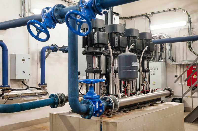 Industrial pump and pipe system with blue valves and black motors in a mechanical room