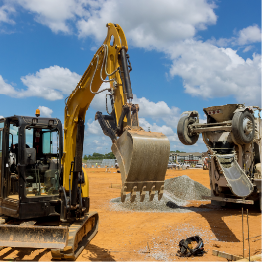 Yellow excavator with raised bucket on a construction site beside a tipped-over machine under a blue sky