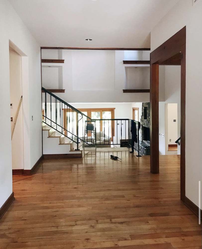 Spacious interior with hardwood floors, a staircase, and open shelving. Natural light, simple design.