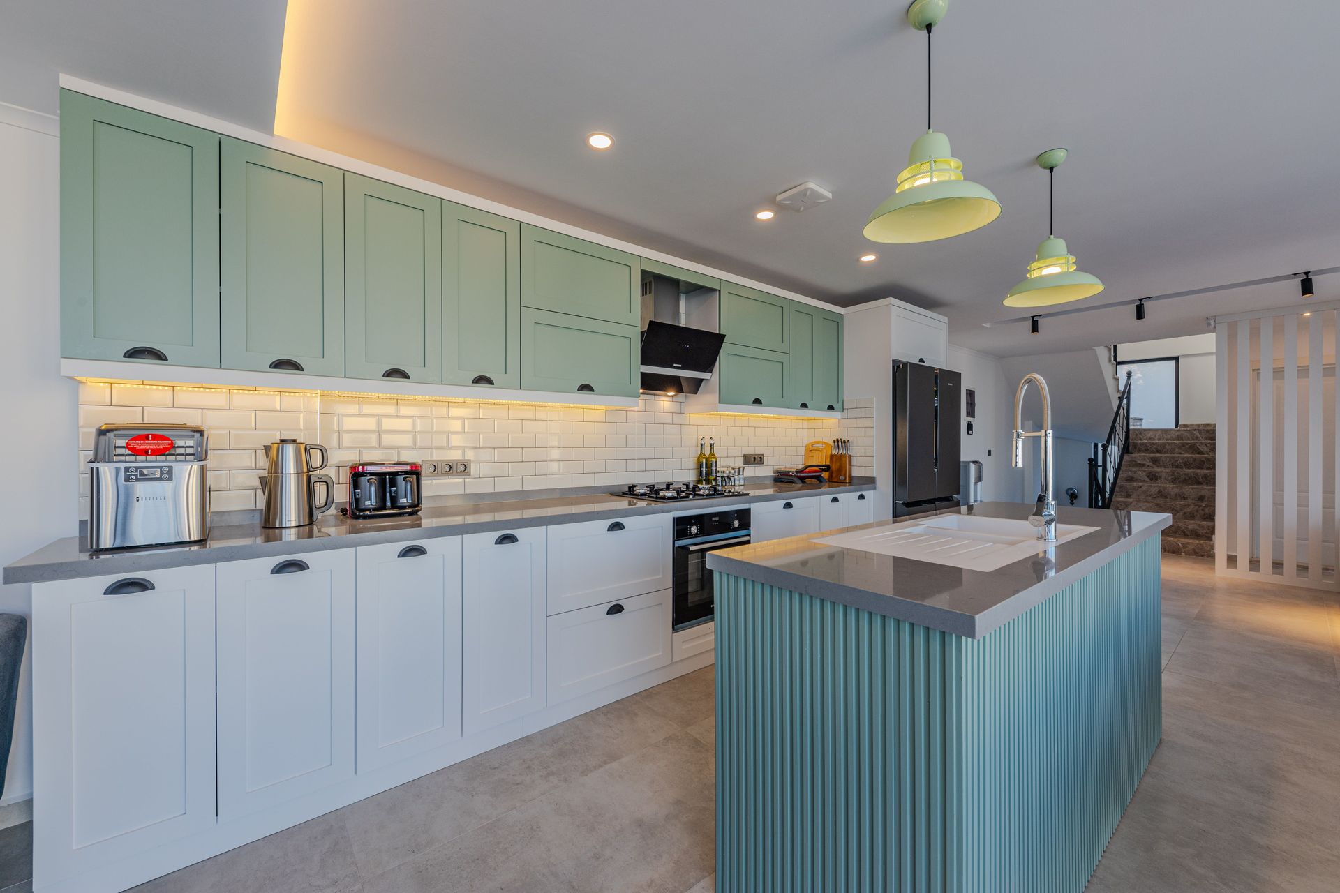 Bright modern kitchen with mint cabinets, marble island, and pendant lights