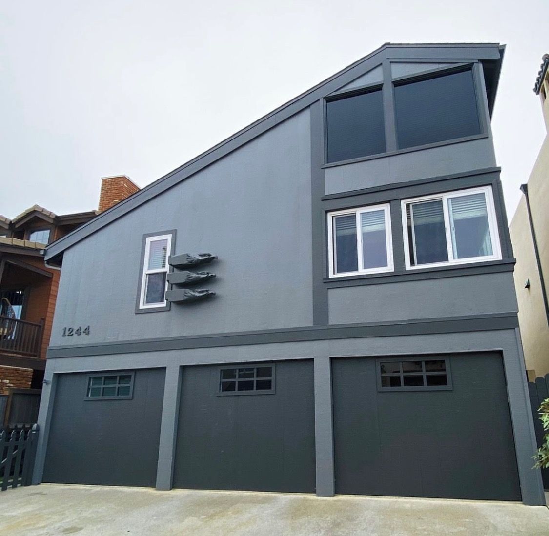 Gray house with three garage doors and angled roof.