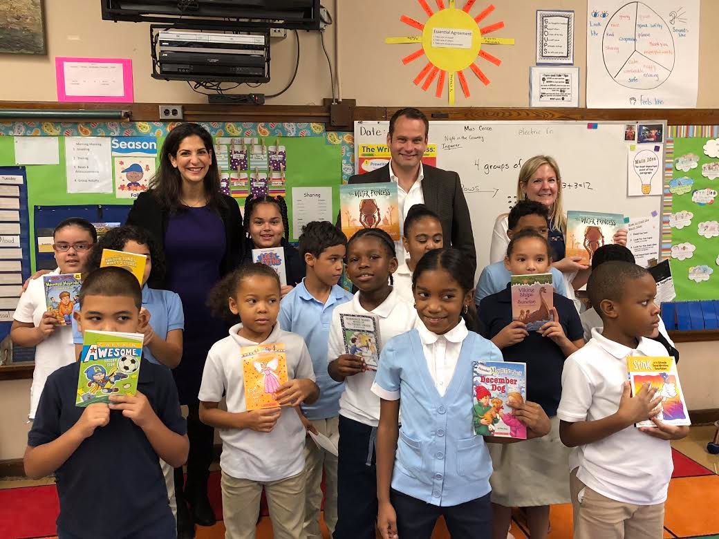 A group of children are holding books in a classroom