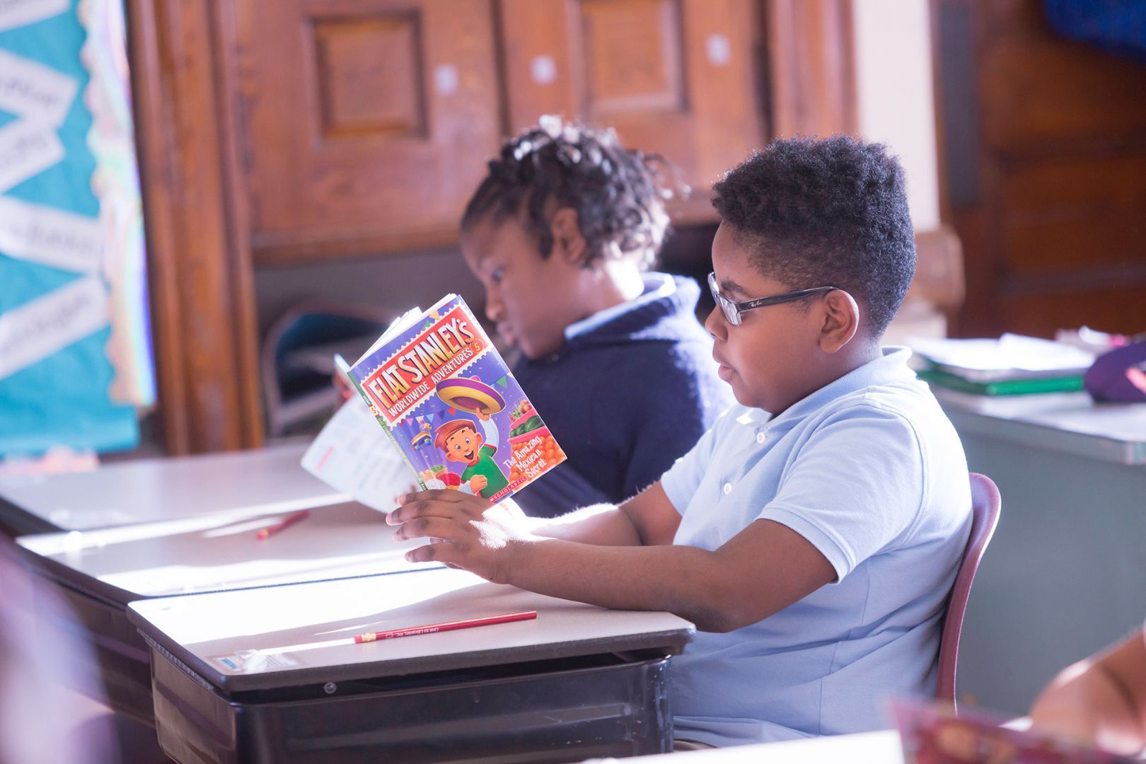 A boy is reading a book in a classroom