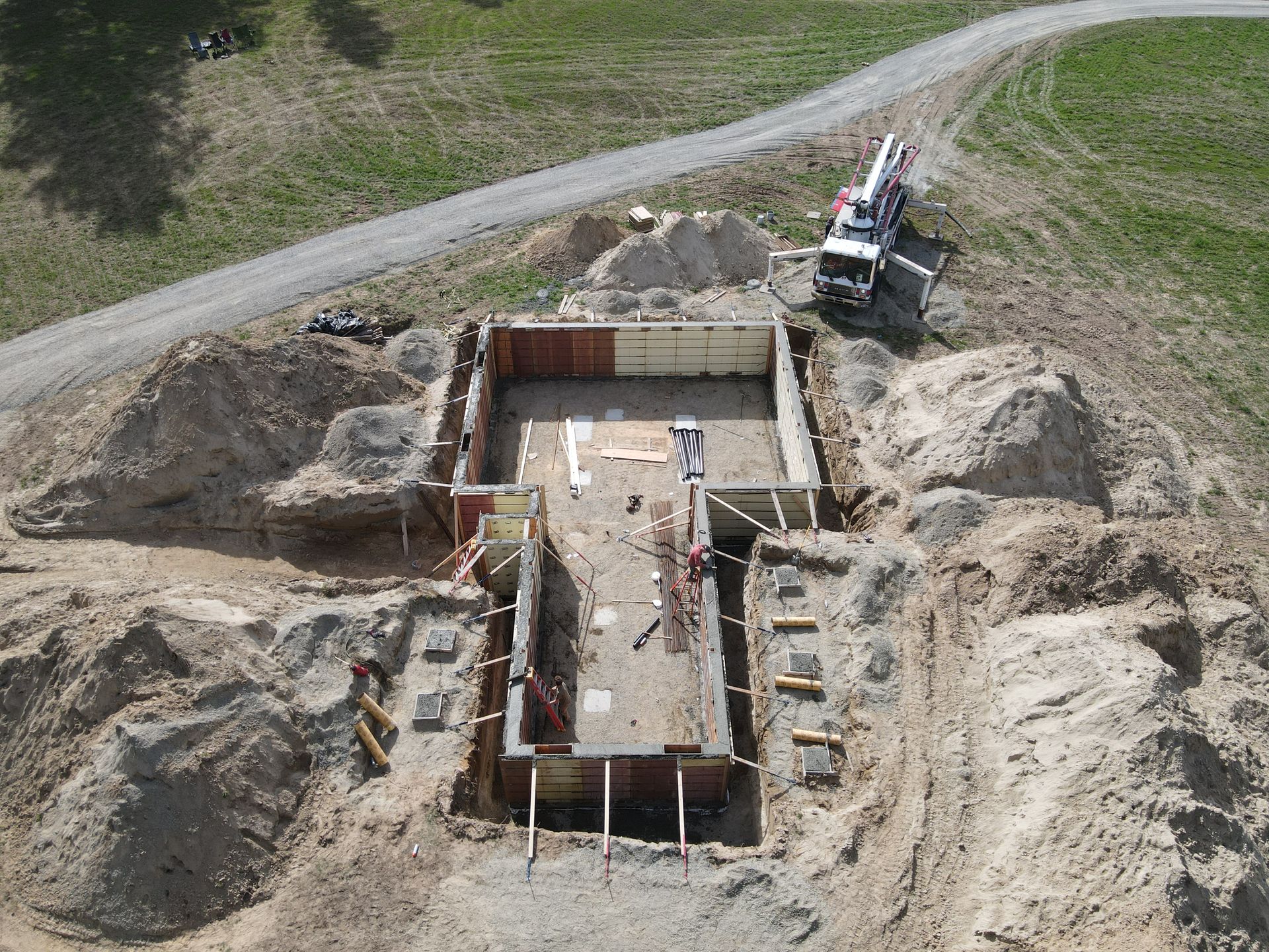 An aerial view of a construction site with a truck pumping concrete. Project done by Raise the Bar Construction