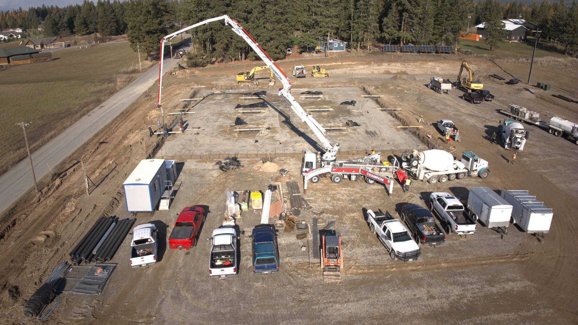An aerial view of a construction site with trucks and a crane. Project done by Raise the Bar Construction