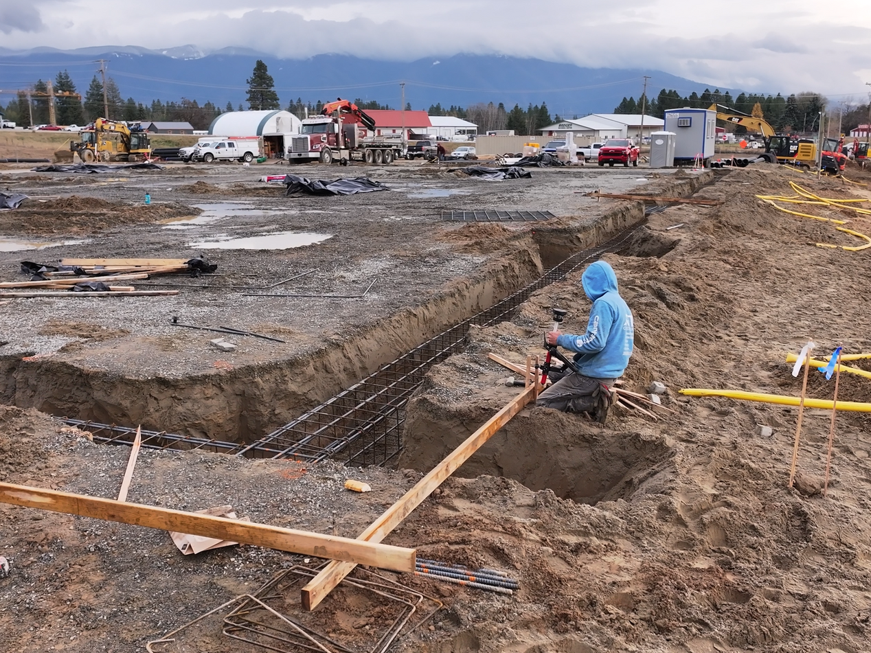 A man in a blue hoodie is working on a construction site. Done by Raise the Bar Construction