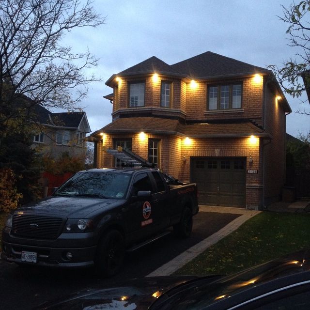 A black truck is parked in front of a brick house