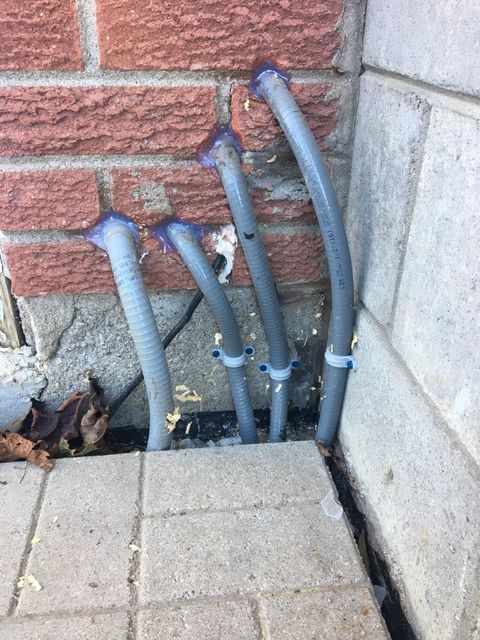 A bunch of pipes are connected to a brick wall
