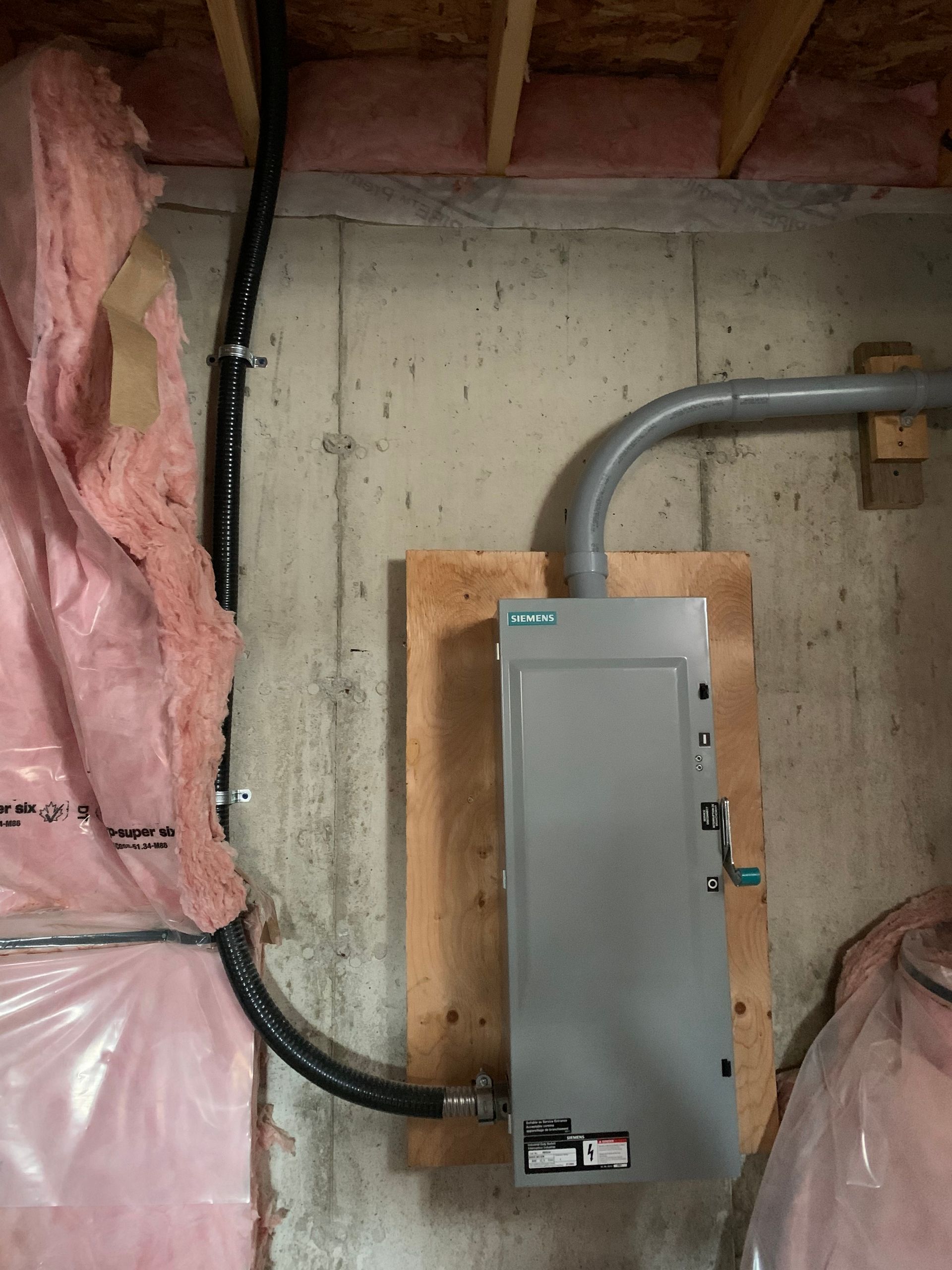 A electrical box is mounted to a wall in a basement.