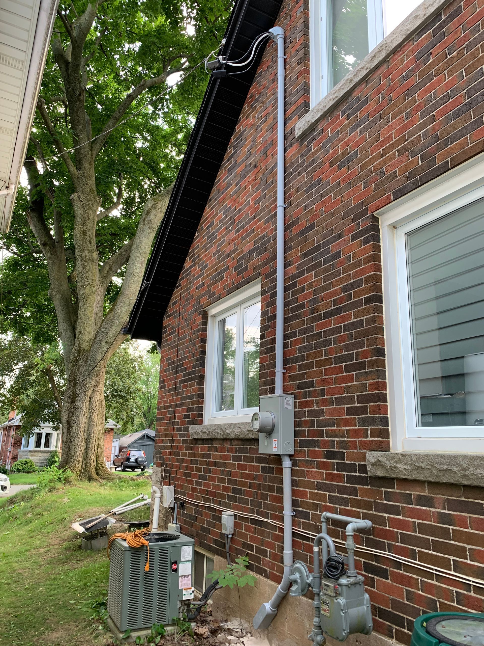 A brick house with a pipe coming out of the side of it.