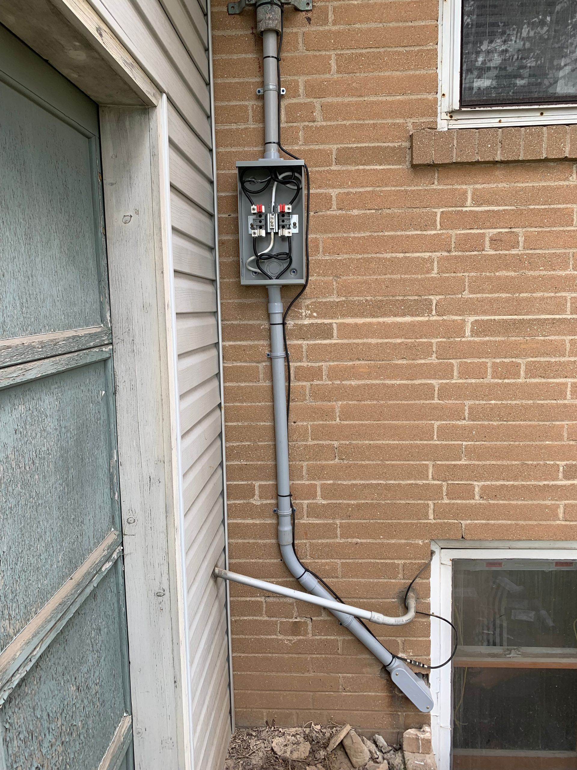 A brick wall with a electrical box attached to it.