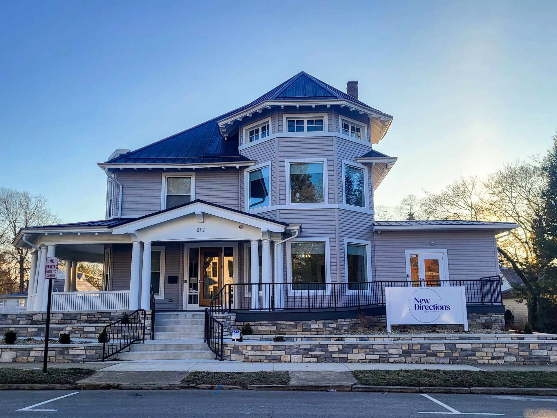 Large two-story Victorian-style house with stone facade and a front porch at dusk