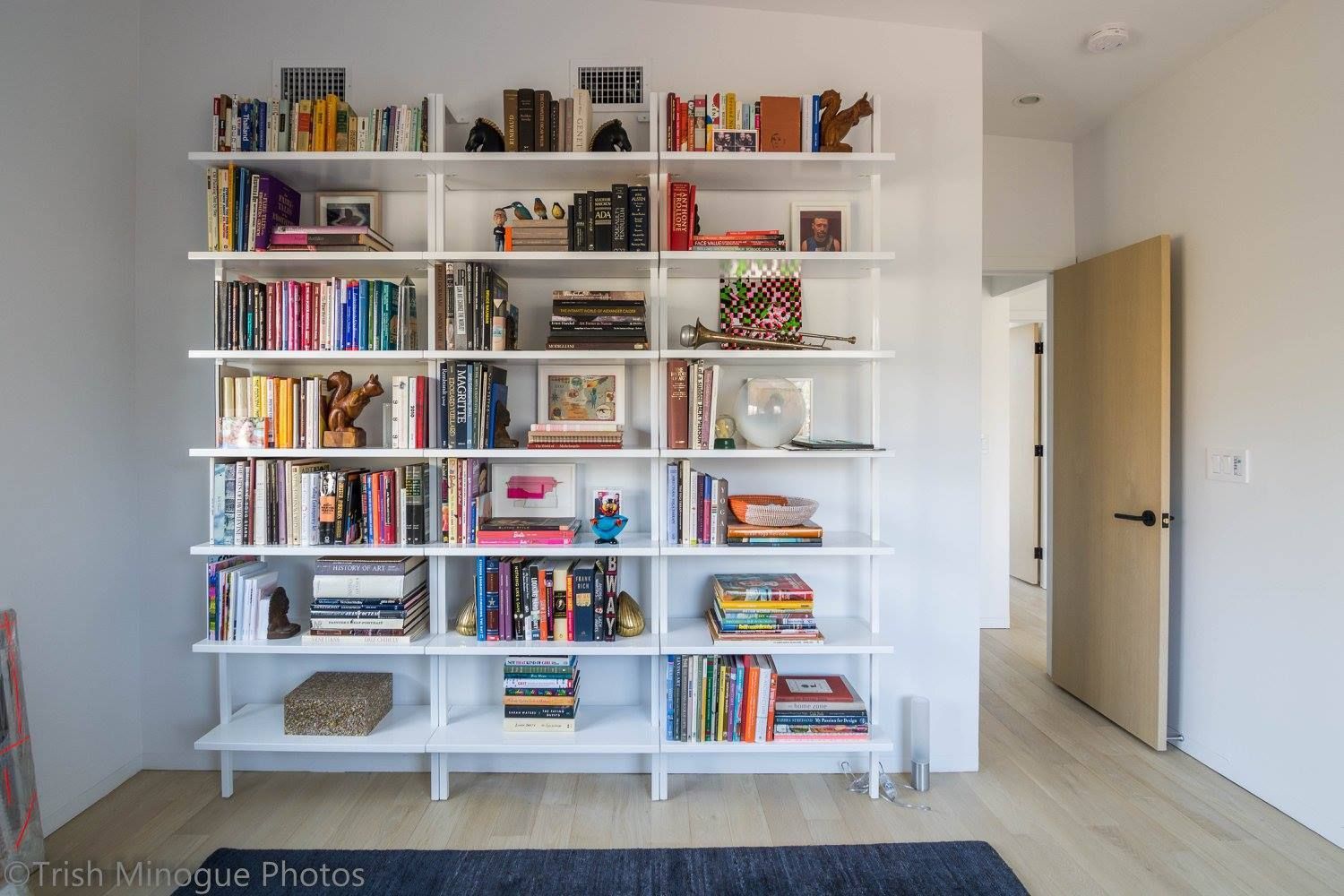 White bookshelf filled with books and decor in a bright, minimalist room