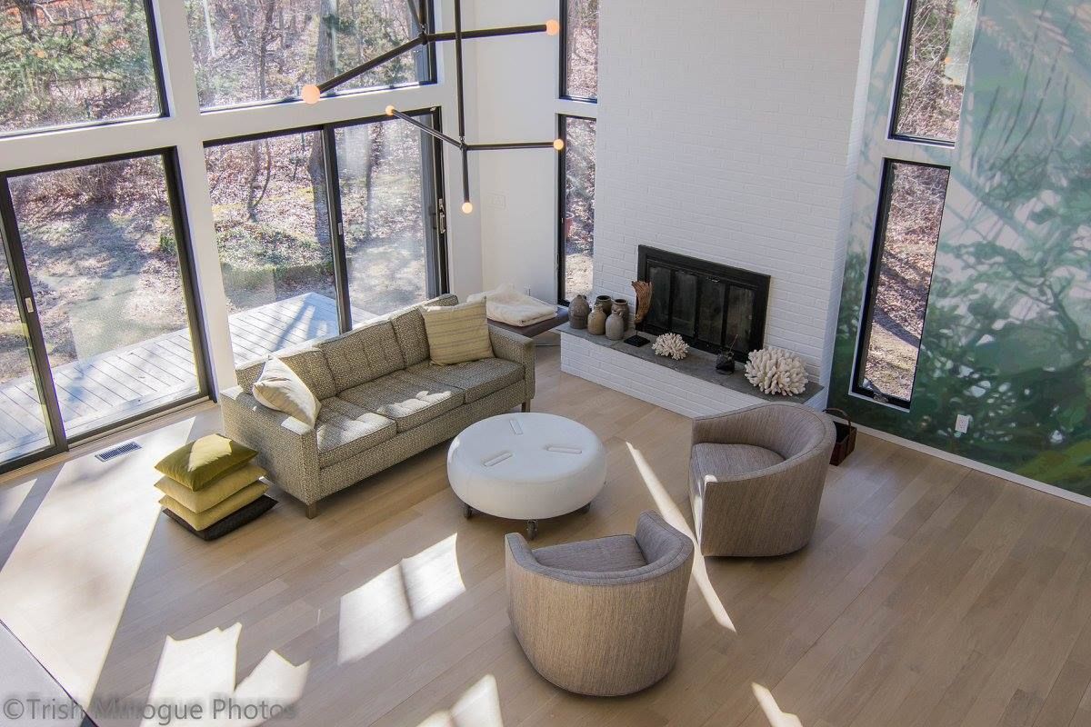 Modern living room with floor-to-ceiling windows, sectional sofa, round coffee table, and fireplace