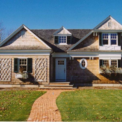Single-story house with gray shingles, white trim, and a brick walkway leading to the front door.