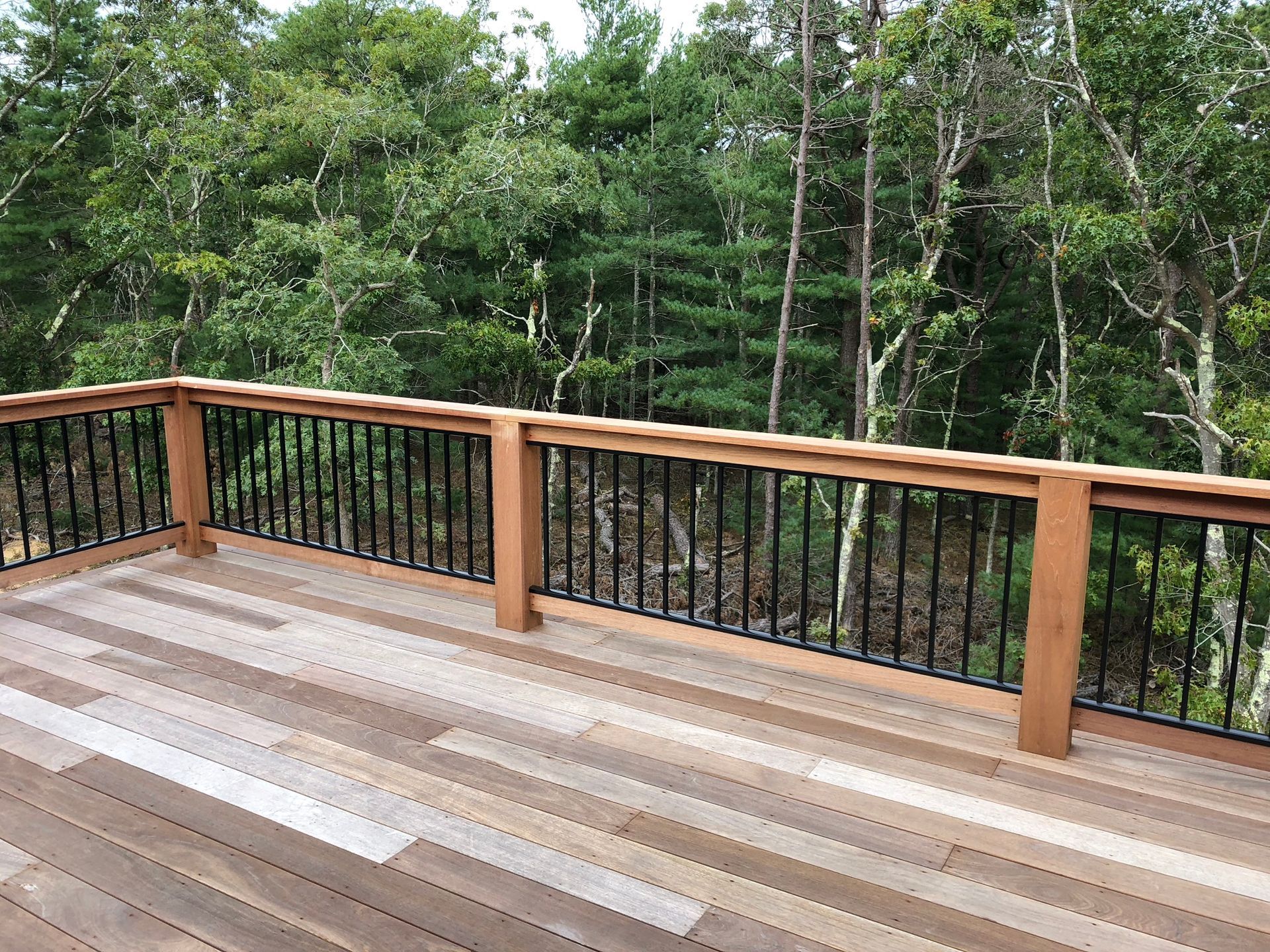 Wooden deck with railing overlooking a green forest.