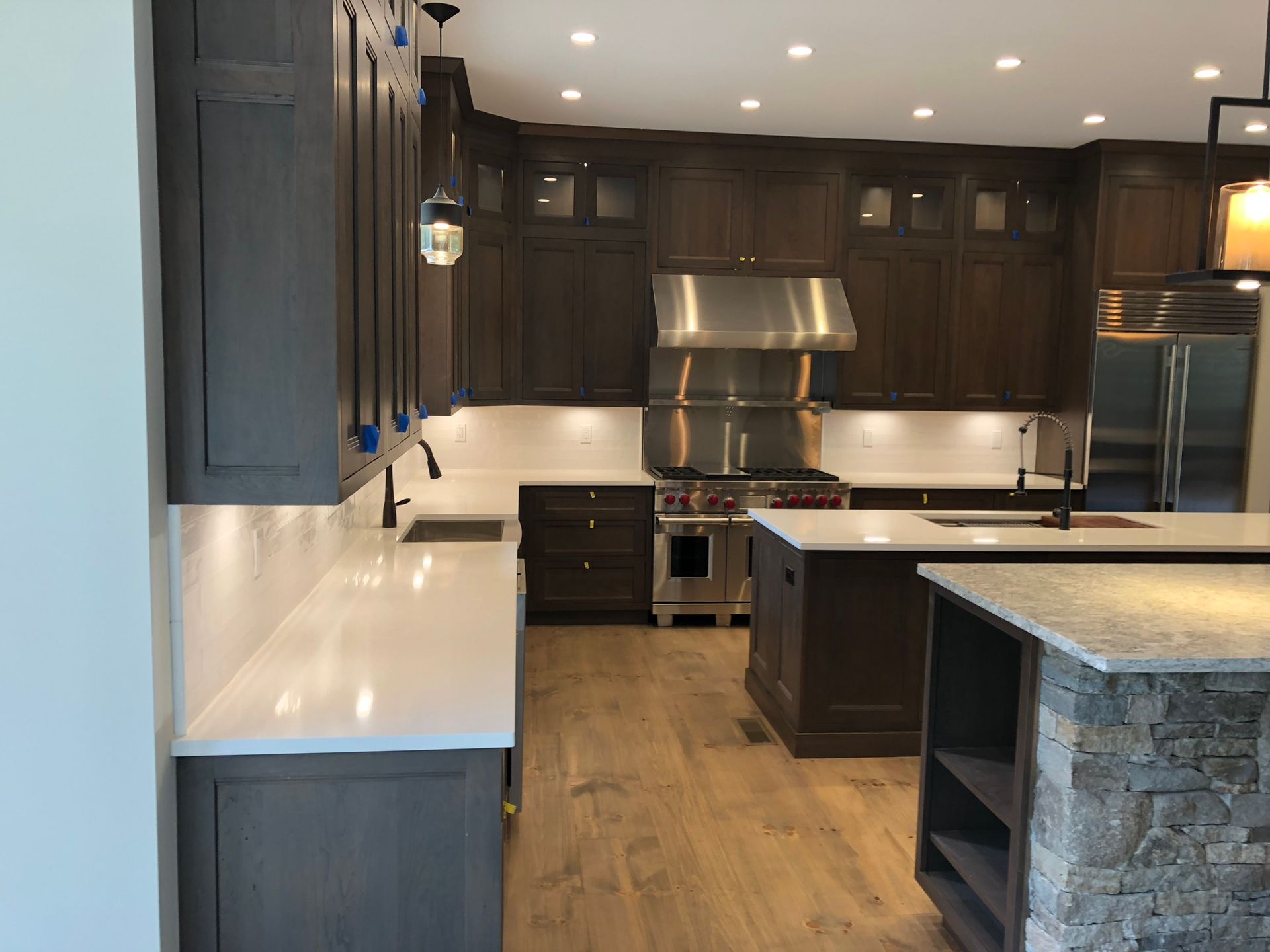 Modern kitchen with dark cabinets, white countertops, stainless steel appliances, and a central island