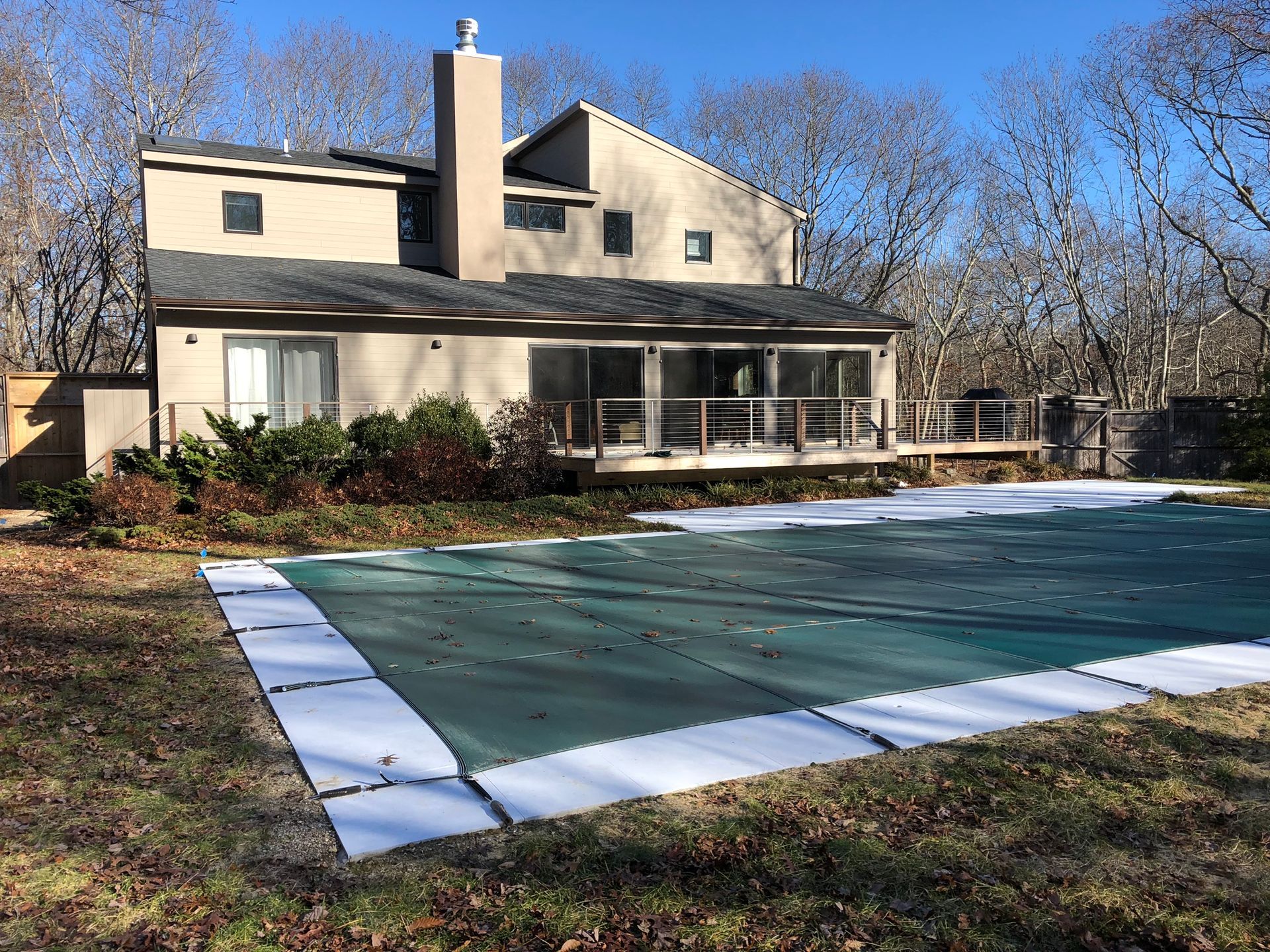 House with covered pool and winter yard, green pool cover in the foreground