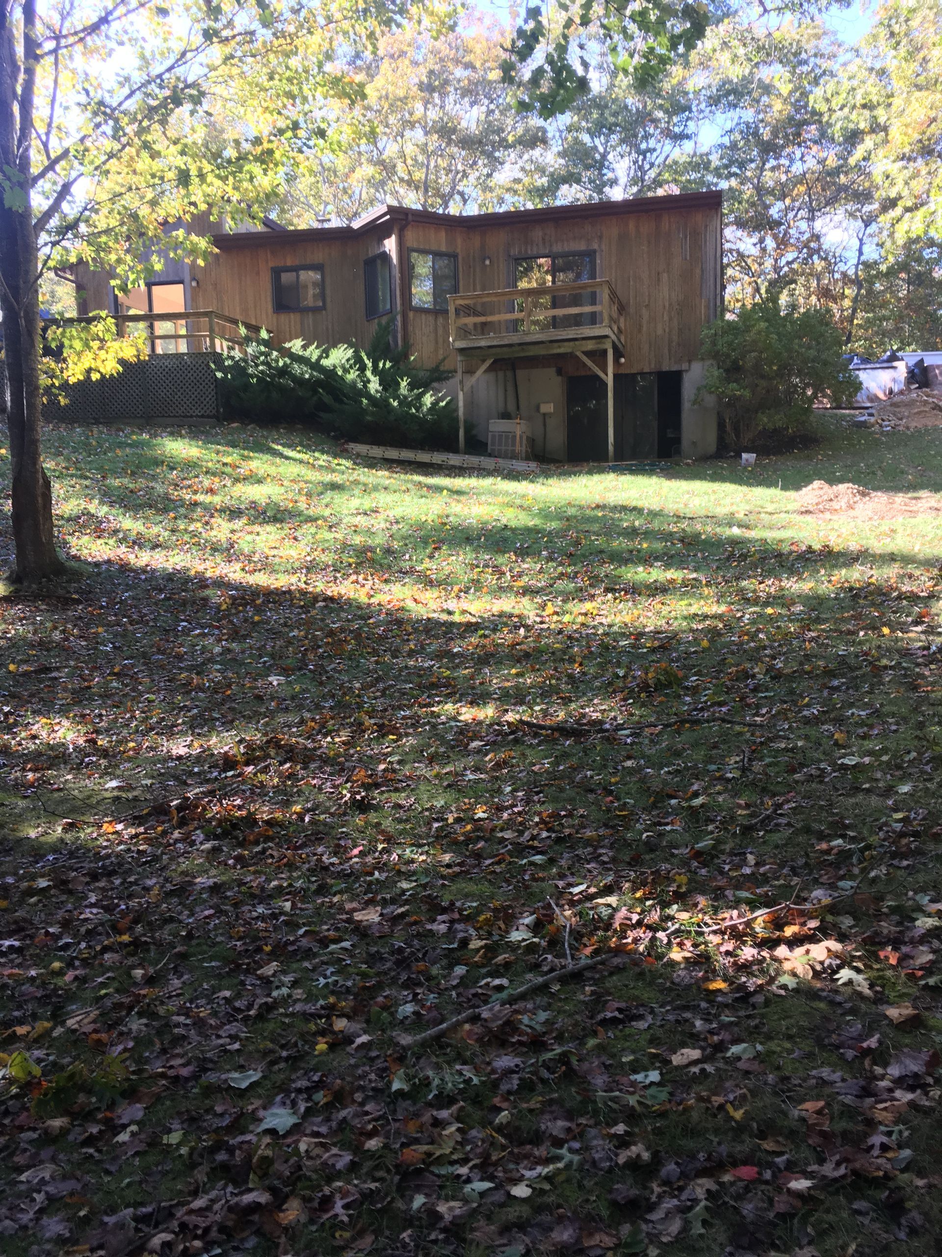 Wooden house with a balcony on a leafy wooded lot in autumn sunlight