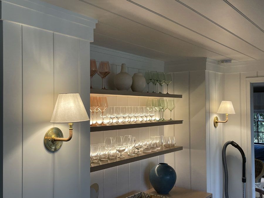 White built-in shelves with glassware, vases, and wall sconces in a softly lit room