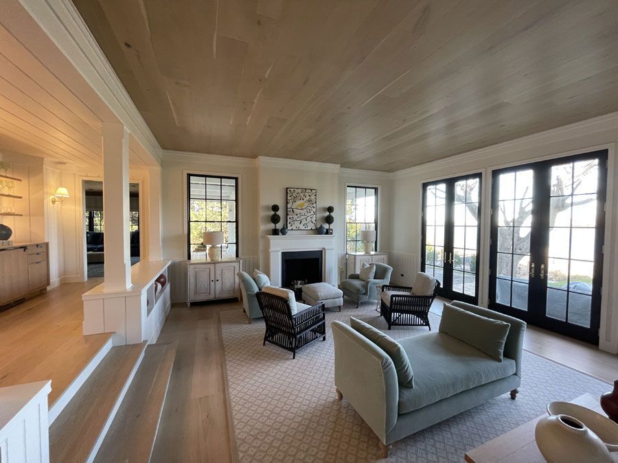 Bright living room with fireplace, light sofas, and large French doors opening to a patio
