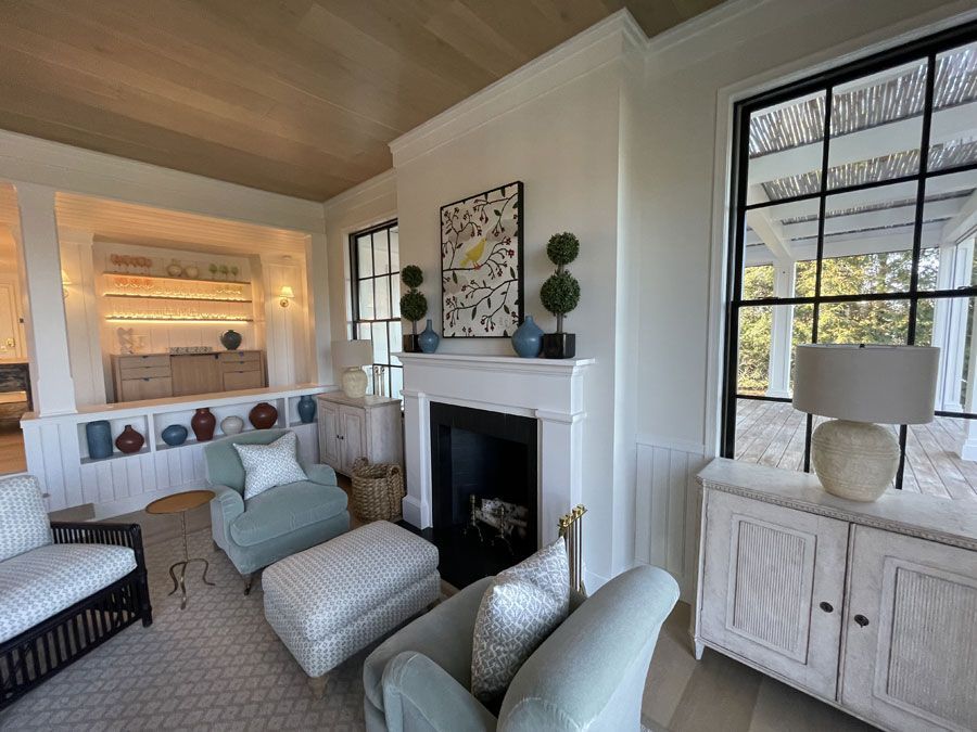 Bright living room with a fireplace, light blue chairs, and large windows.