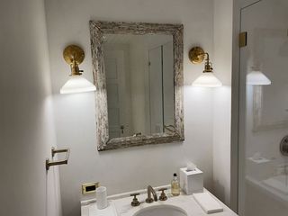 Bathroom vanity with mirror, brass sconces, and white countertop sink