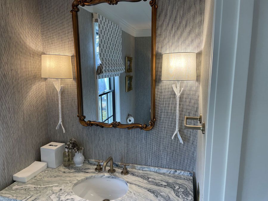 Elegant bathroom vanity with marble countertop, ornate mirror, and wall sconces