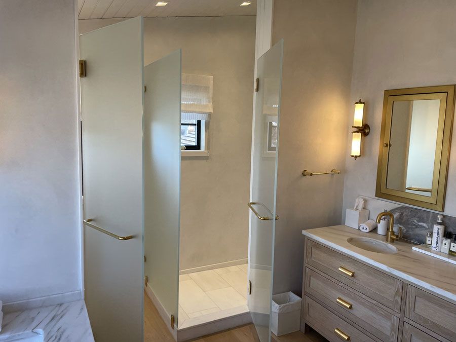 Modern bathroom with open shower door, vanity with mirror, and window in the shower area