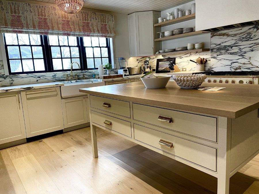 Bright white kitchen with island, wooden countertop, and large window over the sink