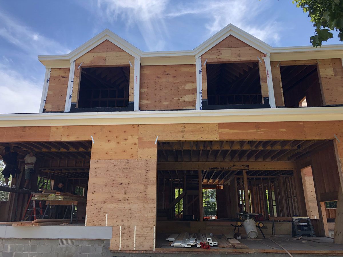 Partially built two-story brick house with open windows and unfinished interior framing