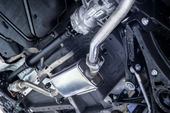 Undercarriage view of a car’s exhaust system and muffler with metal piping and heat shields | Geiger’s Automotive & Diesel Repair