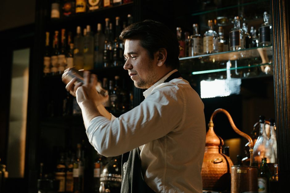 Bartender garnishing a craft cocktail with fresh herbs