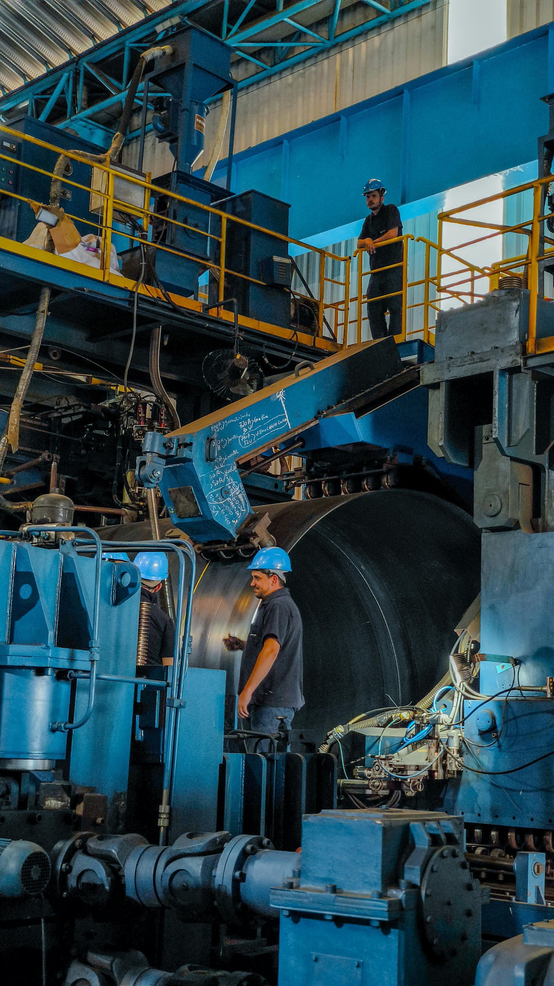 A man is standing on top of a machine in a factory.