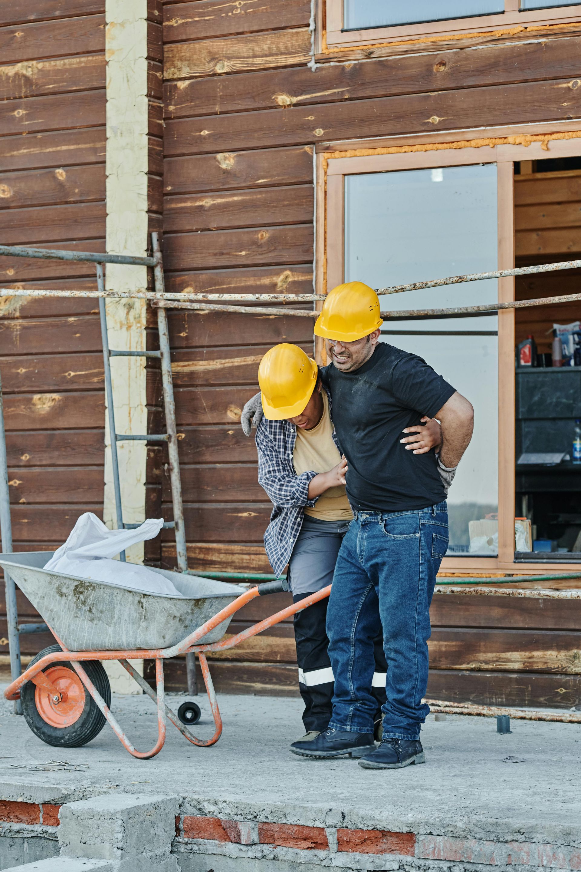 A man is helping a woman in a wheelbarrow at a construction site.