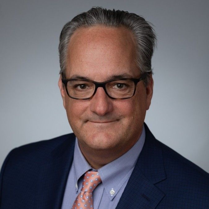 A man in a suit and tie is smiling for the camera.