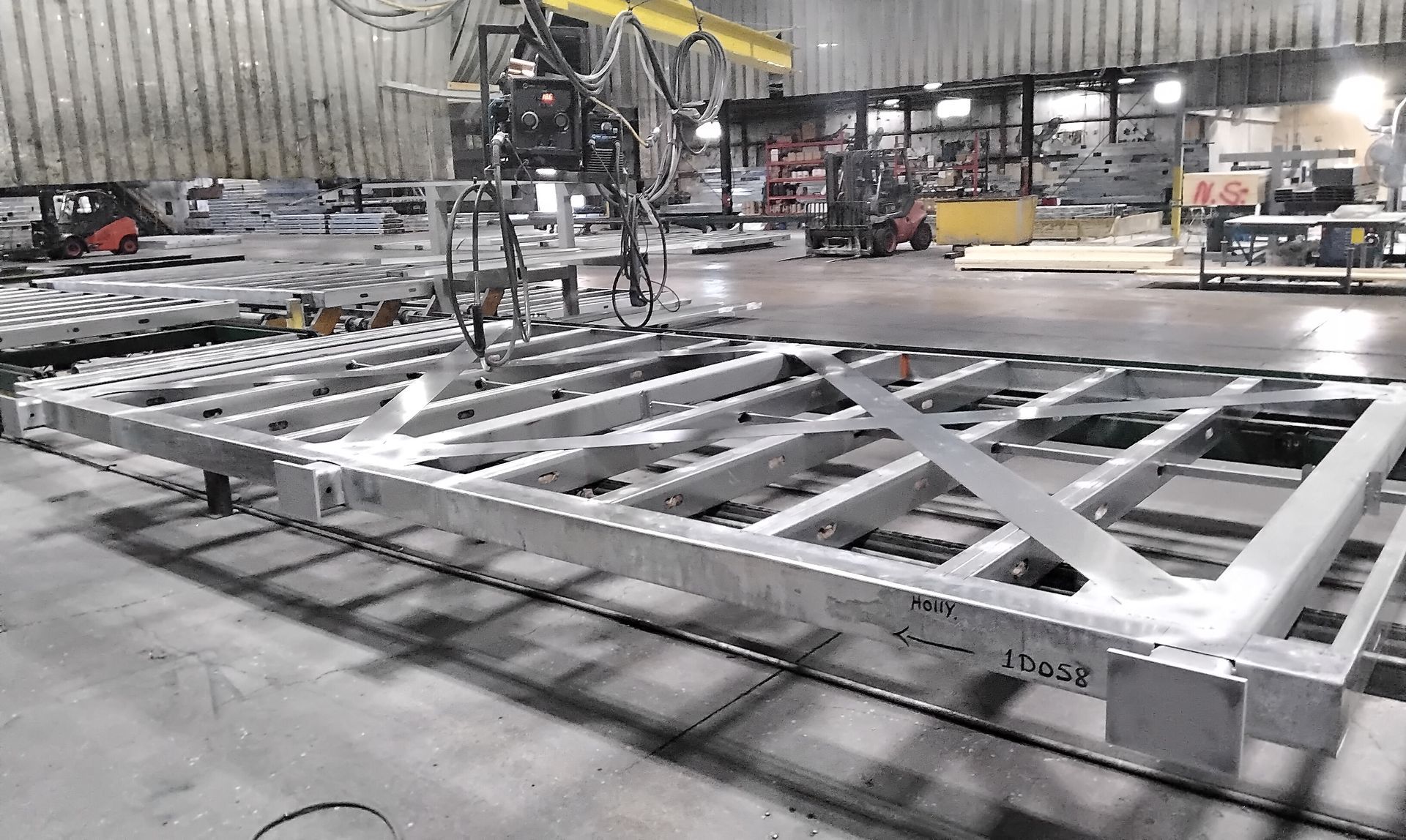 Factory floor with a large silver metal frame under assembly machinery.