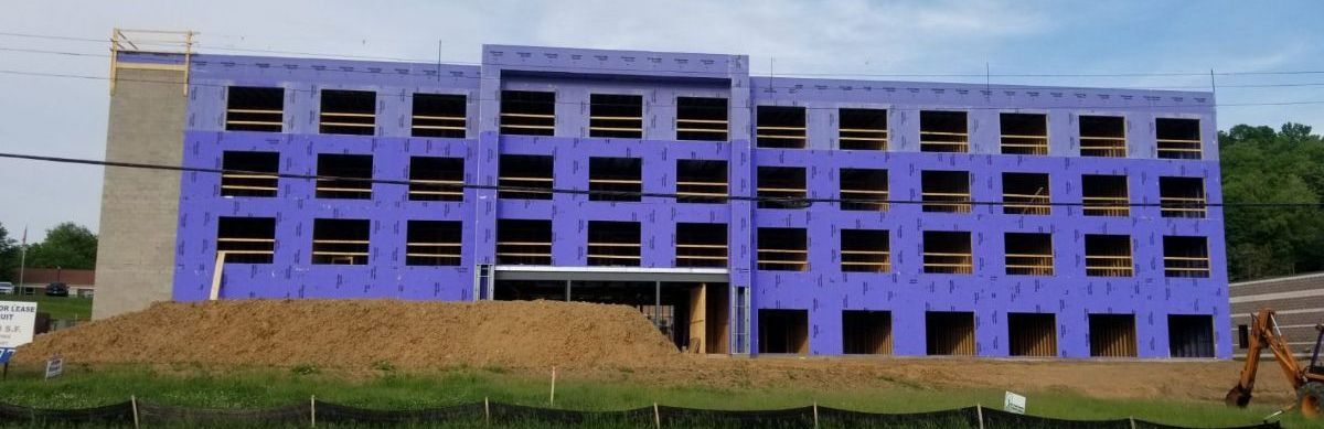 A large building under construction with a lot of windows and purple insulation panels.