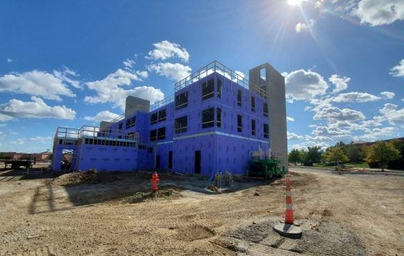 A large purple building is being built in a dirt field.